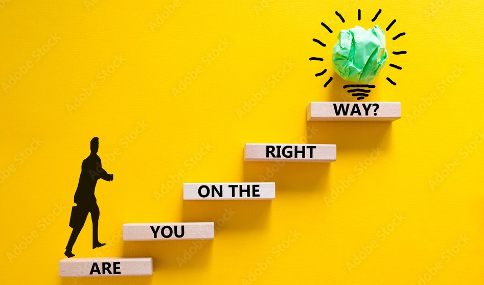 Are YOU on the Right Way A young professional standing at a forked road, looking uncertain about which path to take, while a guiding light illuminates one of the paths, symbolizing clarity and the right direction